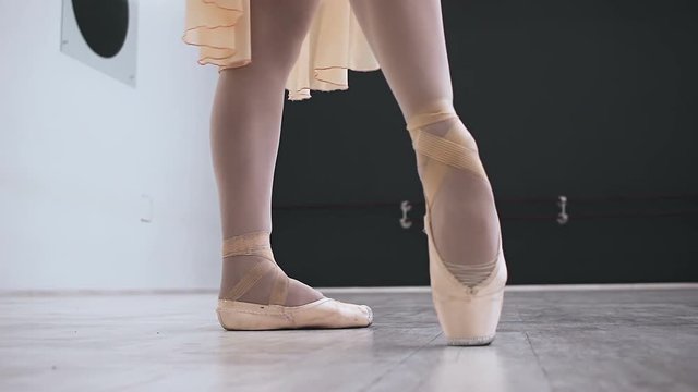 Close up classic ballerina's legs in pointes on white, wooden floor in action