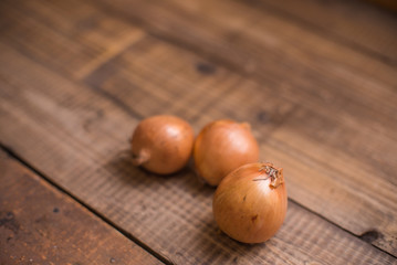 Three onions on wooden table. Place for text. Copy space