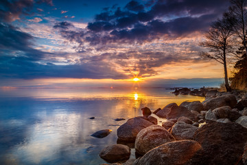 colorful sunset by a lake with a rocky beach