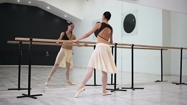Attractive ballerina posing Demi-plie, Grand-plie, Releve in front of mirror