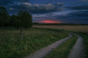 Fototapeta na wymiar gravel road in the country leading towards sunset