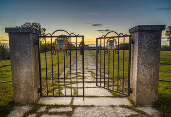 an open iron gate with the sunset as background