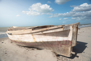 fisherman boat abandoned in the sand on the shore of the beach