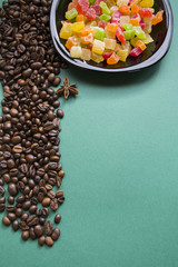 Raw coffee beans and colorful candied fruits on a plate