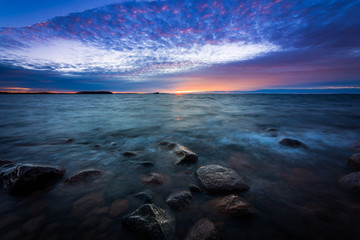 sunset on a rocky beach with waves rushing in