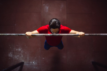 Top view of strong man doing pull ups in gym.