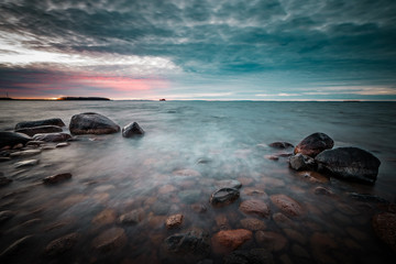 sunset on a rocky beach with waves rushing in