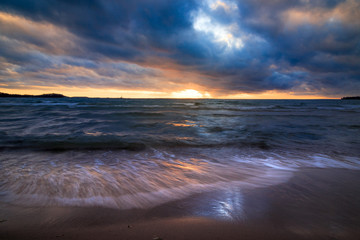 Obraz premium waves rushing onto a sandy beach at sunset