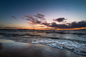 Obraz premium waves rushing onto a sandy beach at sunset