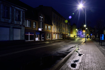 Ulica w mieście w deszczową noc oświetlona lampami.