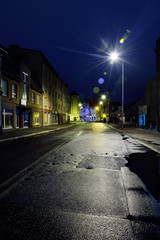 Ulica w mieście w deszczową noc oświetlona lampami.