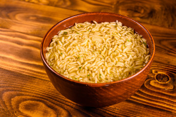 Ceramic bowl with prepared instant noodles on wooden table