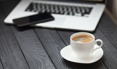 Coffee Cup on the white table on blurred laptop background for Business Concept.