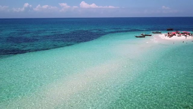 Aerial view of beautiful sand tropical island with white sand beach and tourists. White sand island. Seascape: ocean and beautiful beach paradise. Zanzibar, Tanzania. 4K video. Travel concept