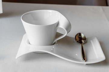 white Cup with place for text on a white saucer with a teaspoon