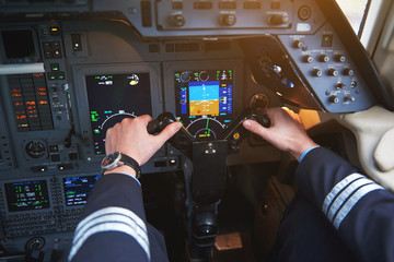 Close up aviator arms navigating aircraft in cabin. Appliance and aviation concept