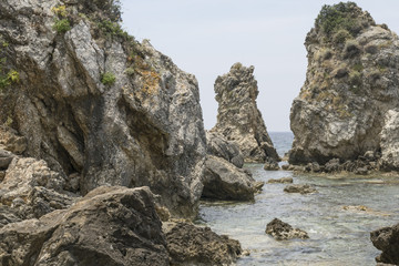 Sea rocks in tidal aves along Ionian sea coast in Paleokastritsa resort in June. Corfu Island, Greece