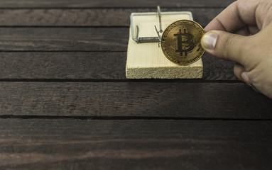 wooden mouse trap and man holds bitcoin