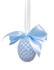 Easter egg decorated with beads and a bow in blue hues, hanging on a white background