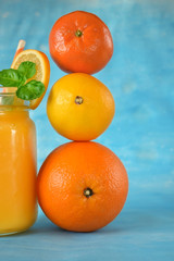 Orange, lemon, mandarin and yellow juice in a glass on blue background