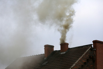 Brown smoke from chimney house due to combustion of coal