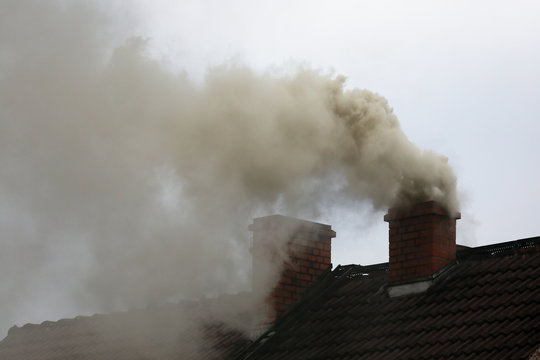 Brown smoke from chimney house due to combustion of coal