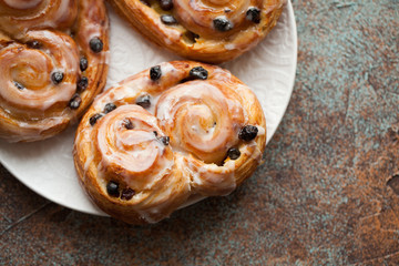 Fresh buns with raisins and icing on old rusty background. Top view with copy space