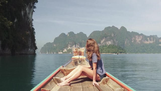 Young Happy Mixed Race Girl Sitting and Relaxing on Traditional Thai Wooden Long Tail Boat at Khao Sok Lake. Phang Nga Province, Thailand.