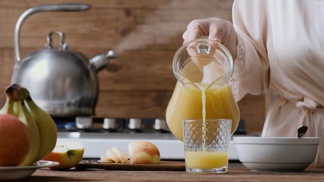 Cinemagraph - Young woman pouring the orange juice into a glass. Breakfast. Motion Photo.