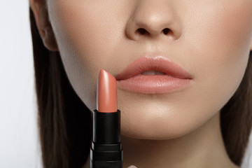 Close up of sensual girl holding pink lipstick near her mouth. Lip beauty concept