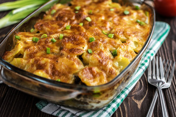Potato casserole with meat and mushrooms on a wooden background