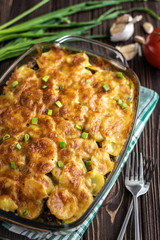 Potato casserole with meat and mushrooms on a wooden background