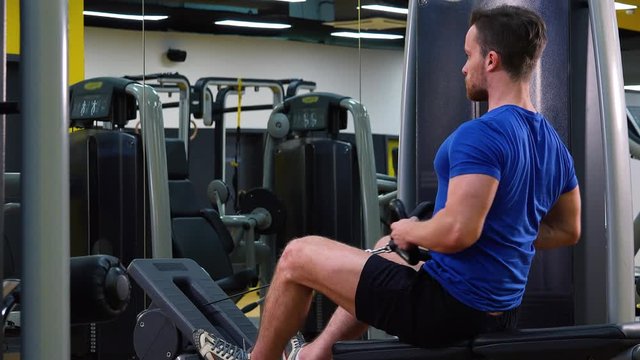A young fit man trains on a rowing machine in a gym