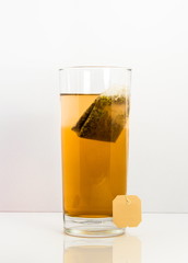 orange fruit tea glas with bag isolated with white background and reflection