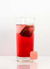 red fruit tea glas with bag isolated with white background and reflection
