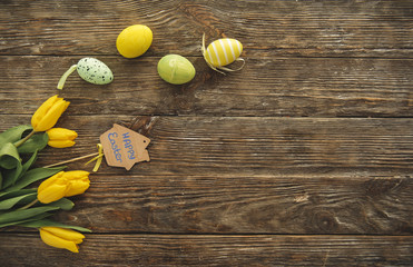 Top view of bunch of spring flowers and colored eggs on the timbered table. Copy space in right side