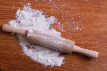 wooden rolling pin for dough on wooden suface with powder 