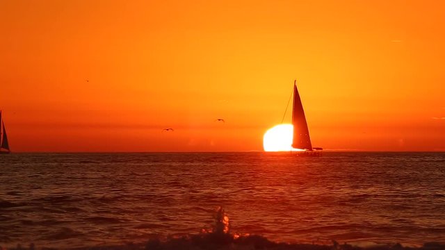 Orange sunset with sailboat on the ocean