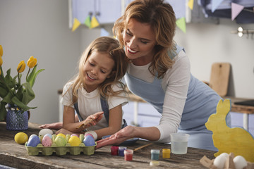 Obraz premium Great job. Satisfied mom and child getting ready for easter. They are looking at dozen of colored eggs with proud