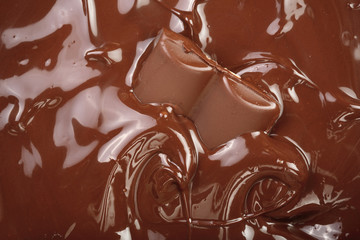 Melted chocolate and pieces of chocolate bar as a background closeup