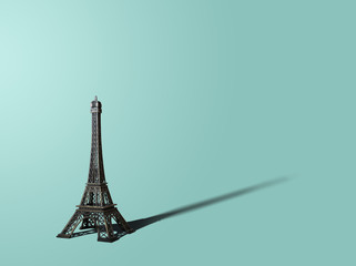 Figurine of the Eiffel Tower on a pastel background. On a blue, turquoise, green pastel background is a figurine of the Eiffel Tower. A view from the front of the Eiffel Tower. Pastel background.