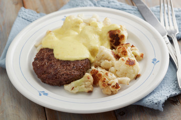 Meat burger with cauliflowers under cheese sauce
