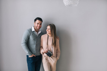 Portrait of young stylish fashion couple against the gray wall.