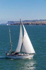 Fototapeta premium White small sailboat at peaceful clear sea scene under sunlight