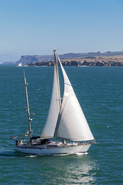 White small sailboat at peaceful clear sea scene under sunlight