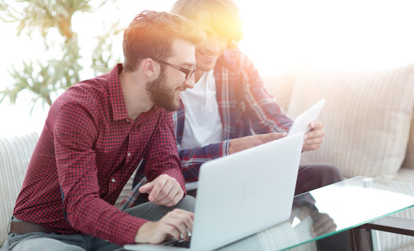 Portrait of two web designers discussing a project in front of a laptop
