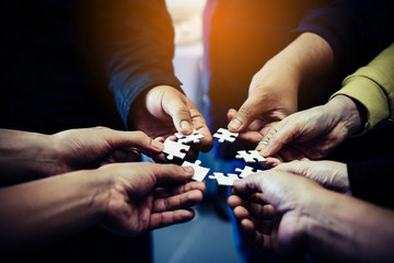 Close-up photo of businesspeople holding jigsaw puzzle