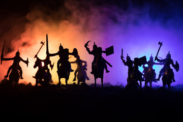 Fototapeta na wymiar Medieval battle scene with cavalry and infantry. Silhouettes of figures as separate objects, fight between warriors on dark toned foggy background. Night scene.