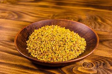 Ceramic plate with bee pollen on wooden table