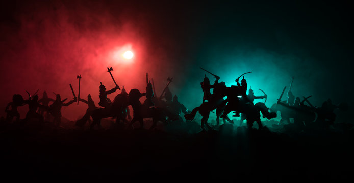 Medieval battle scene with cavalry and infantry. Silhouettes of figures as separate objects, fight between warriors on dark toned foggy background. Night scene.